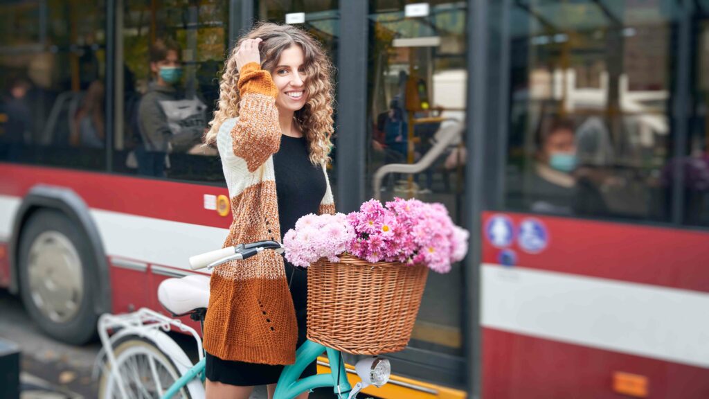 Eine lächelnde Frau mit einem Fahrrad steht vor einem Bus.