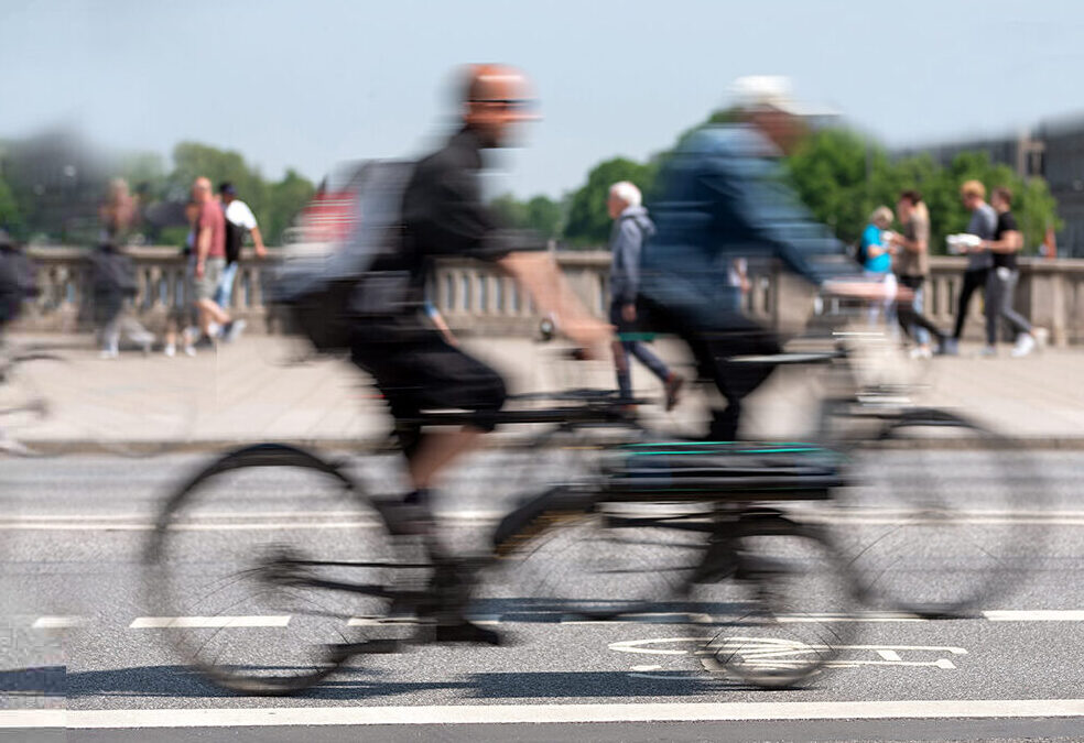 Eine Brücke überqueren mehrere Personen auf dem Fahrrad und einige Fußgänger.