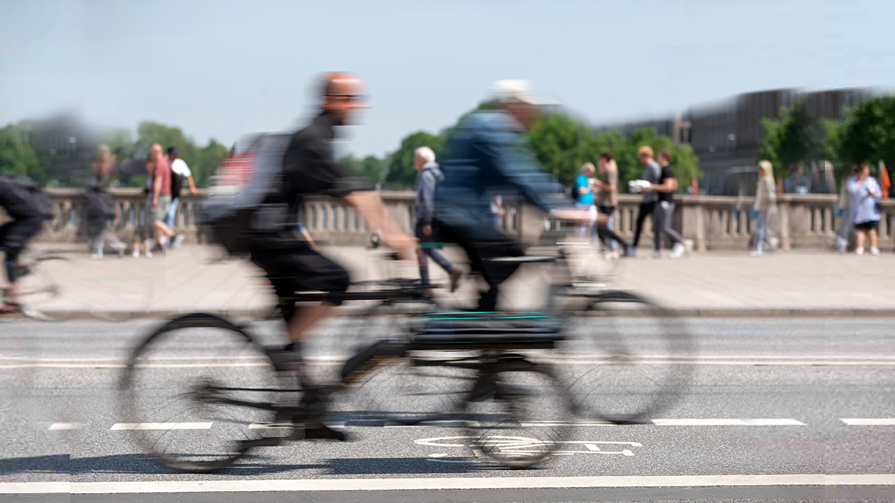 Eine Brücke überqueren mehrere Personen auf dem Fahrrad und einige Fußgänger.