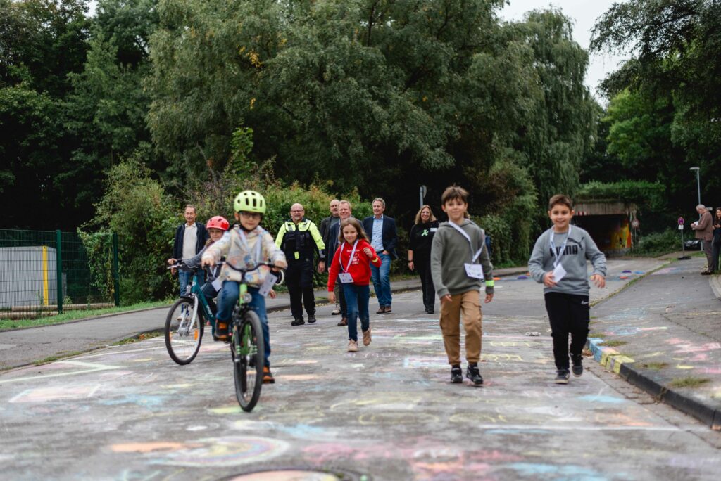 Kinder fahren Fahrrad und laufen auf der Schulstraße. 